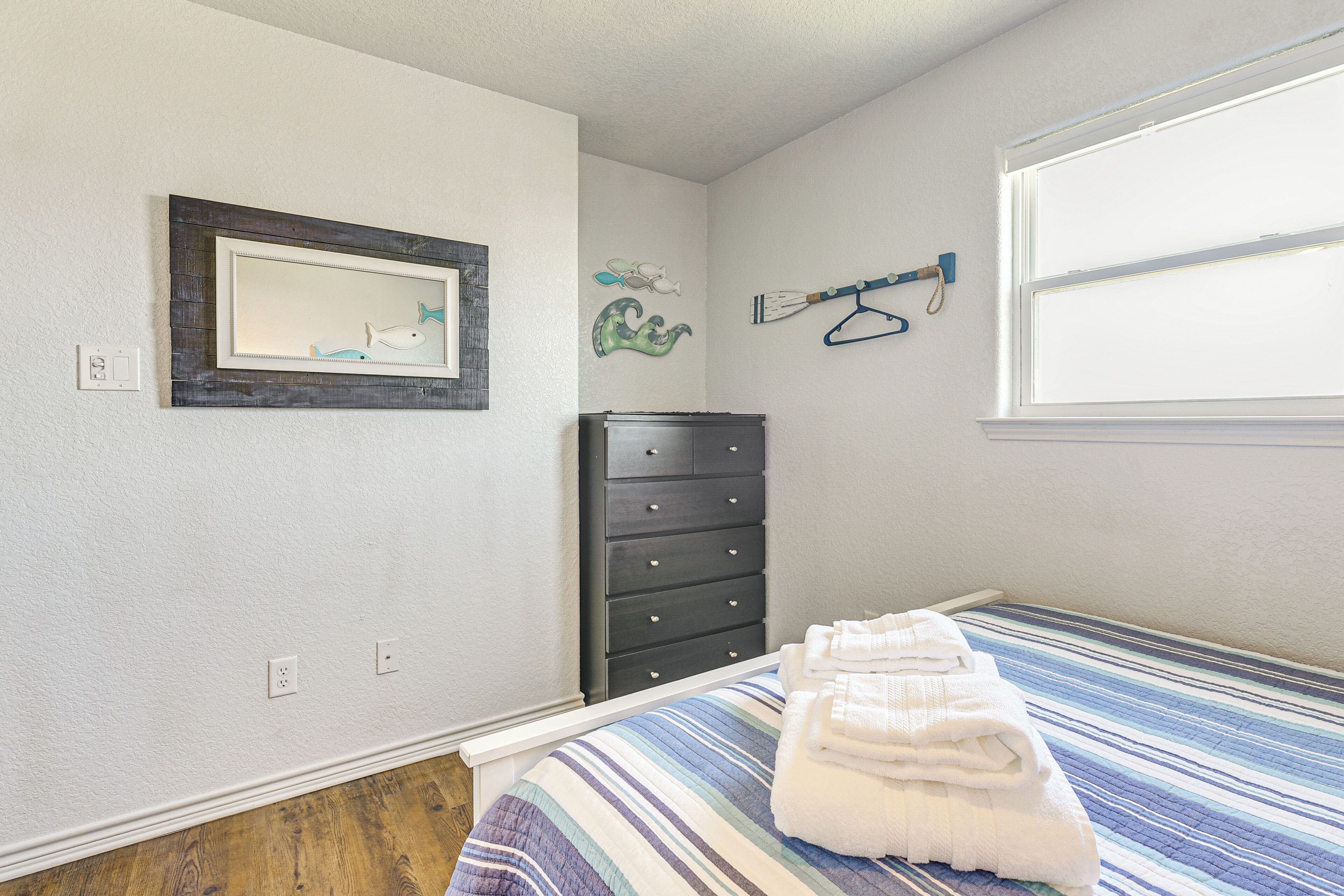A bedroom with a bed, a dresser, a mirror, and wall decorations.