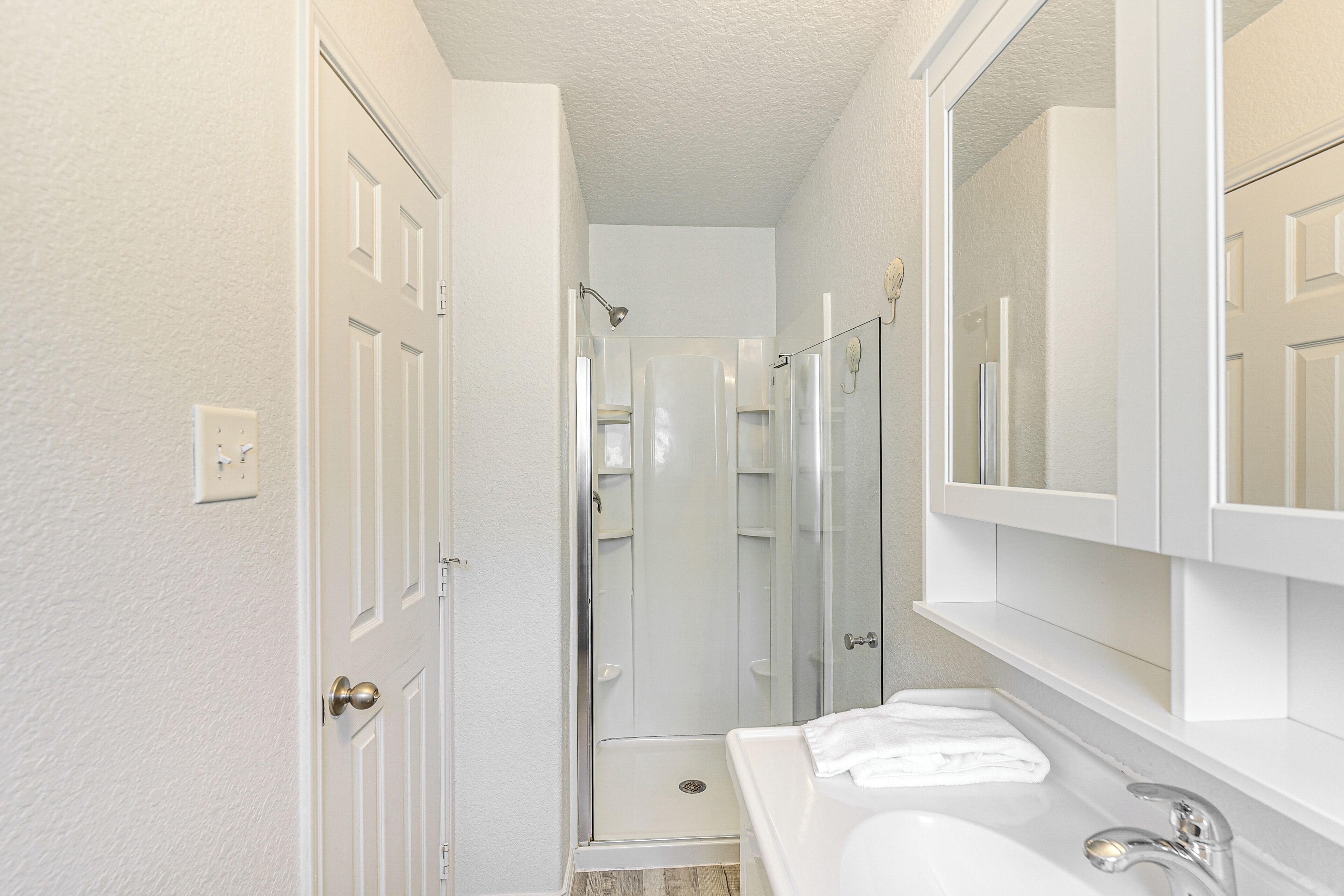 A bathroom with a white sink, a mirror, and a shower.