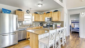 A modern kitchen with wooden cabinets, stainless steel appliances, and a central island with bar stools. - 1 Block to Surfside Beach: Home w/ Gulf Views! (Freeport)