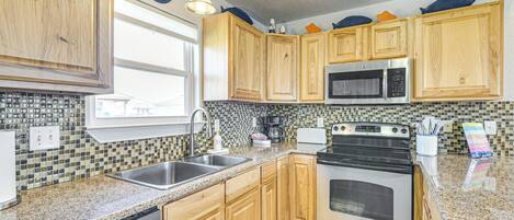 A kitchen with wooden cabinets, a stainless steel microwave, an oven, and a dishwasher.