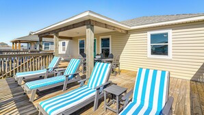 A deck with blue-striped lounge chairs and a covered seating area. - 1 Block to Surfside Beach: Home w/ Gulf Views! (Freeport)