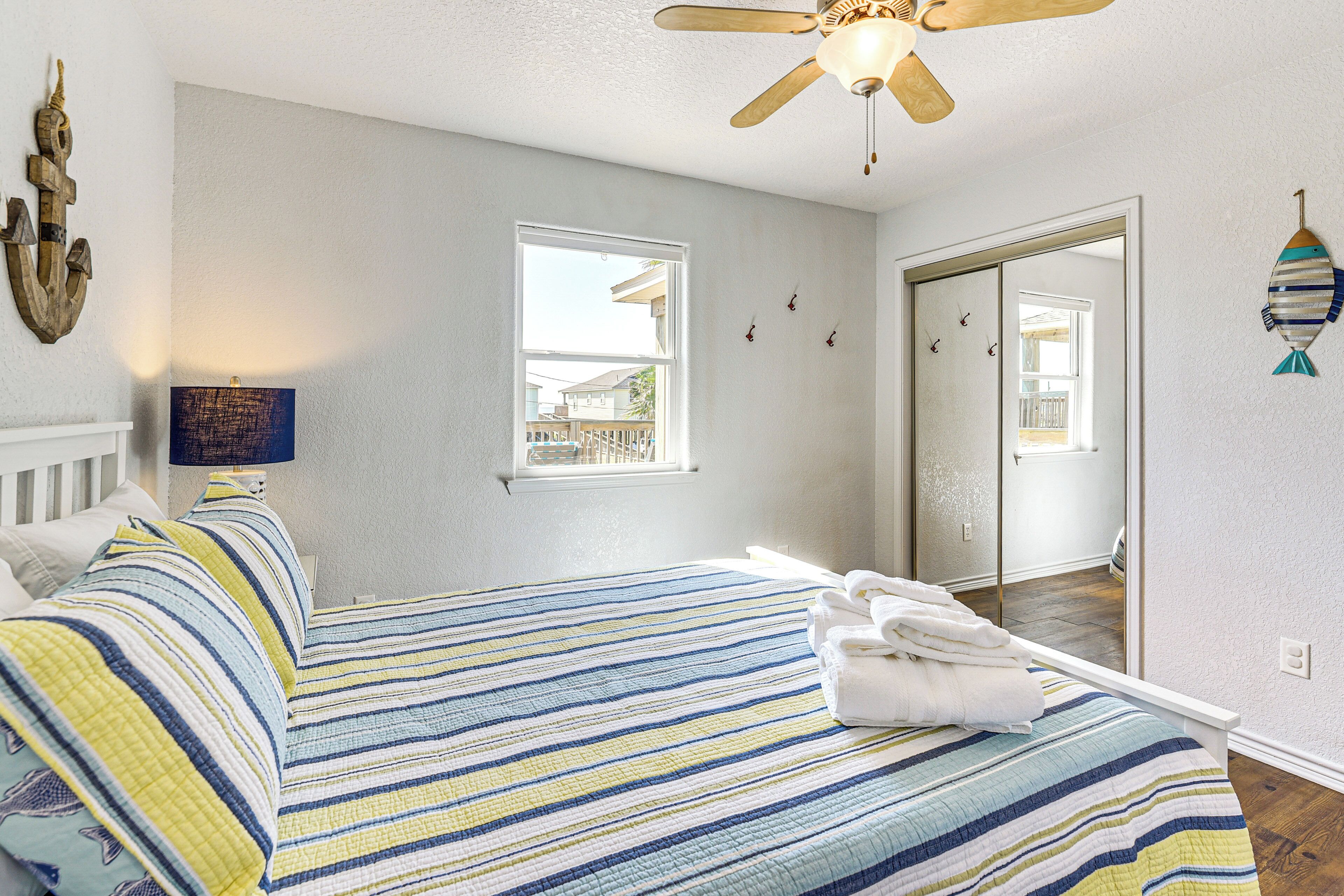 A bedroom with a bed, a ceiling fan, a window, and a door.