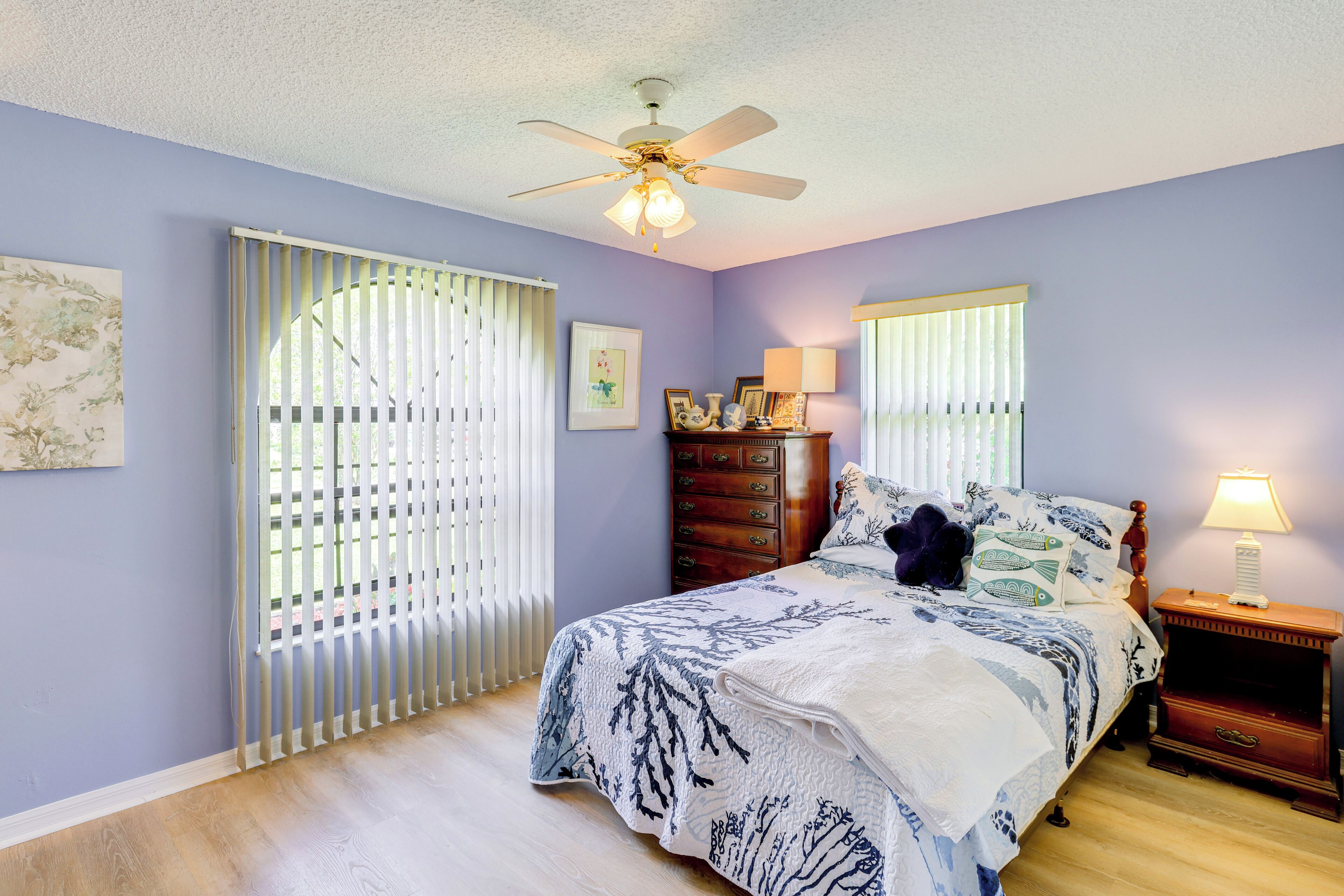 A bedroom with a bed, a nightstand, a dresser, and a ceiling fan.