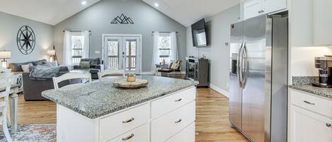 Una cocina amplia con una isla grande, armarios blancos y un refrigerador de acero inoxidable.
