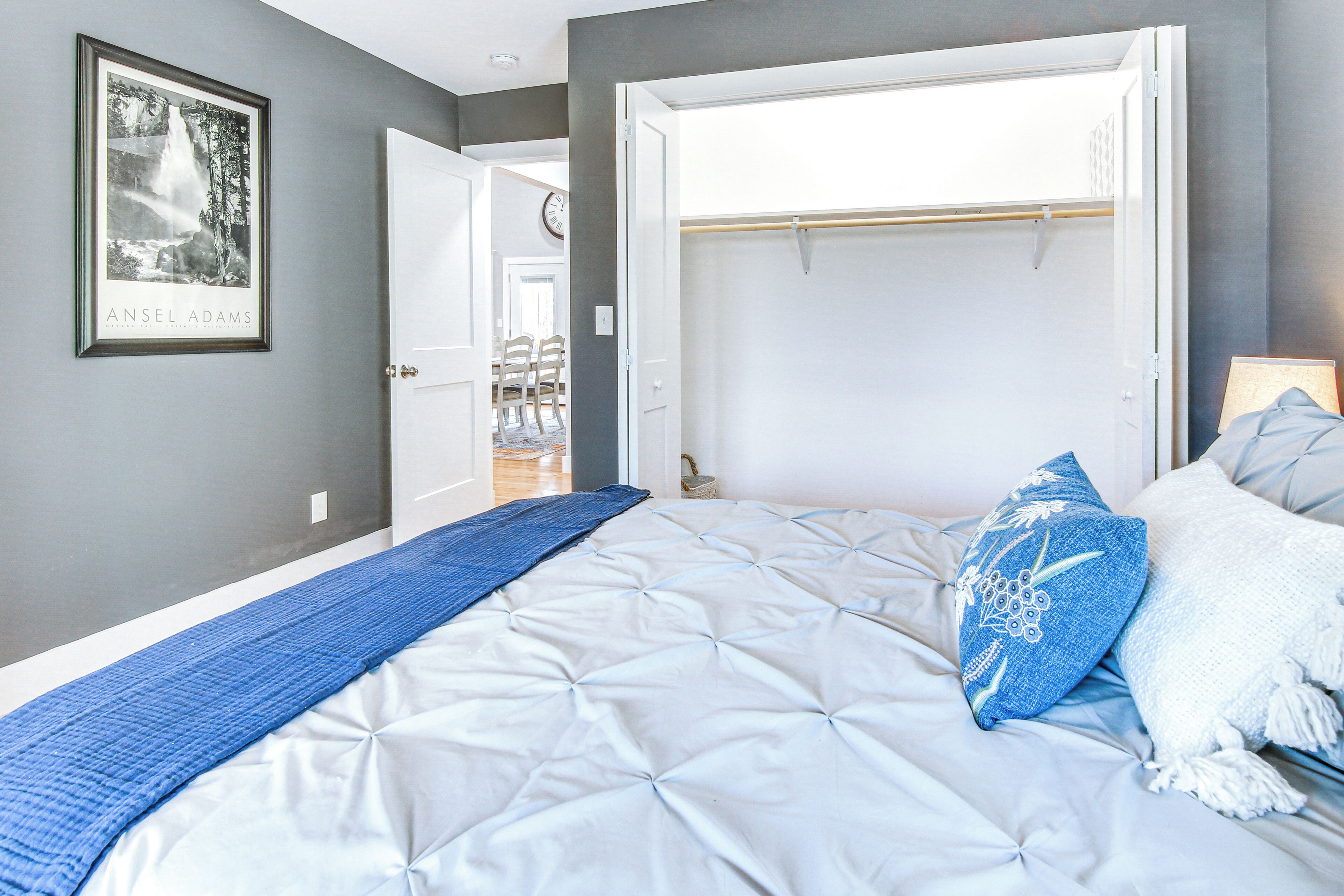 A bedroom with a large bed, a walk-in closet, and a framed picture on the wall.