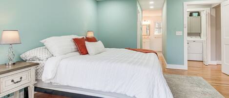 A bedroom with a bed, bedside tables, a lamp, and a walk-in closet.