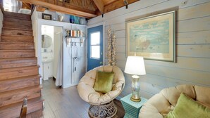 A wooden staircase leading to a bathroom with a sink and mirror. A chair with a cushion is placed near a table with a lamp. - Fish On-site: Okeechobee Cabin w/ Pool Access (Okeechobee)