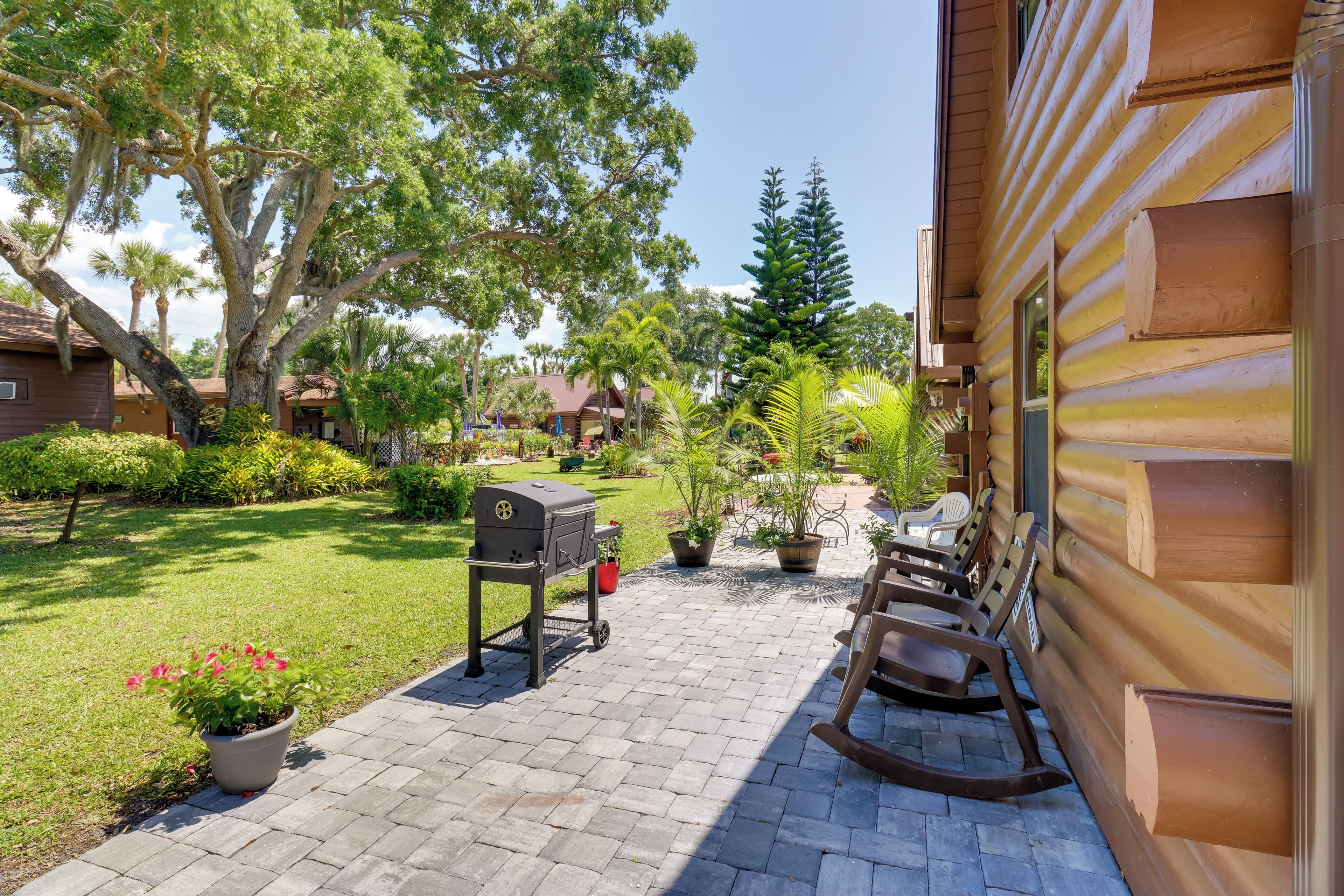 A patio with a grill, rocking chairs, and potted plants.