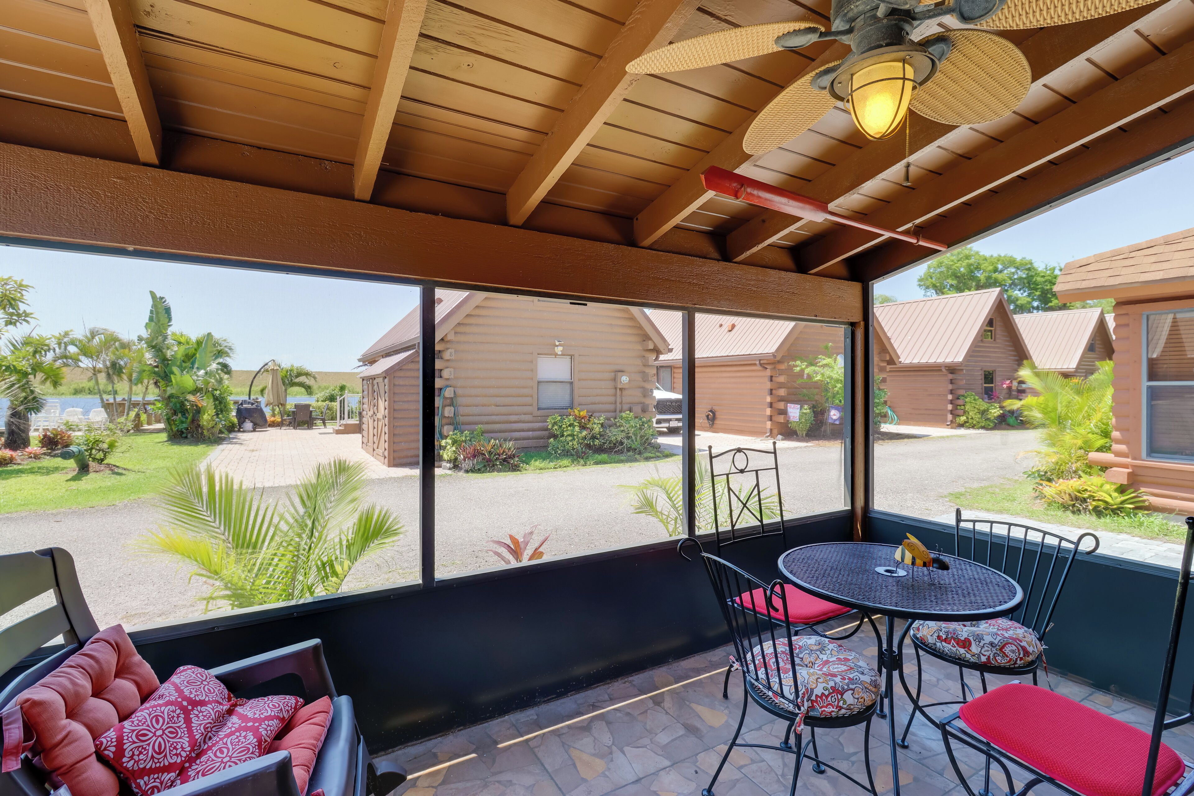 A covered patio with a table and chairs, a ceiling fan, and a view of a residential area with houses and greenery.