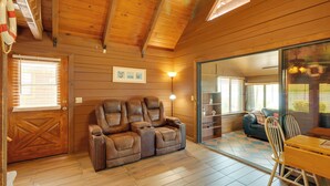 A wooden interior with a leather sofa, a dining table, and a glass door leading to another room. - Lake Okeechobee Cabin w/ Boat Launch & Patio (Okeechobee)