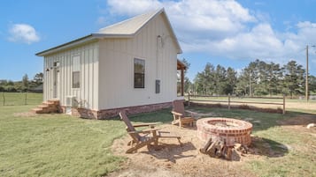 Situated in a grassy area, this charming building features a front porch and a chimney, perfect for relaxation and social gatherings.
