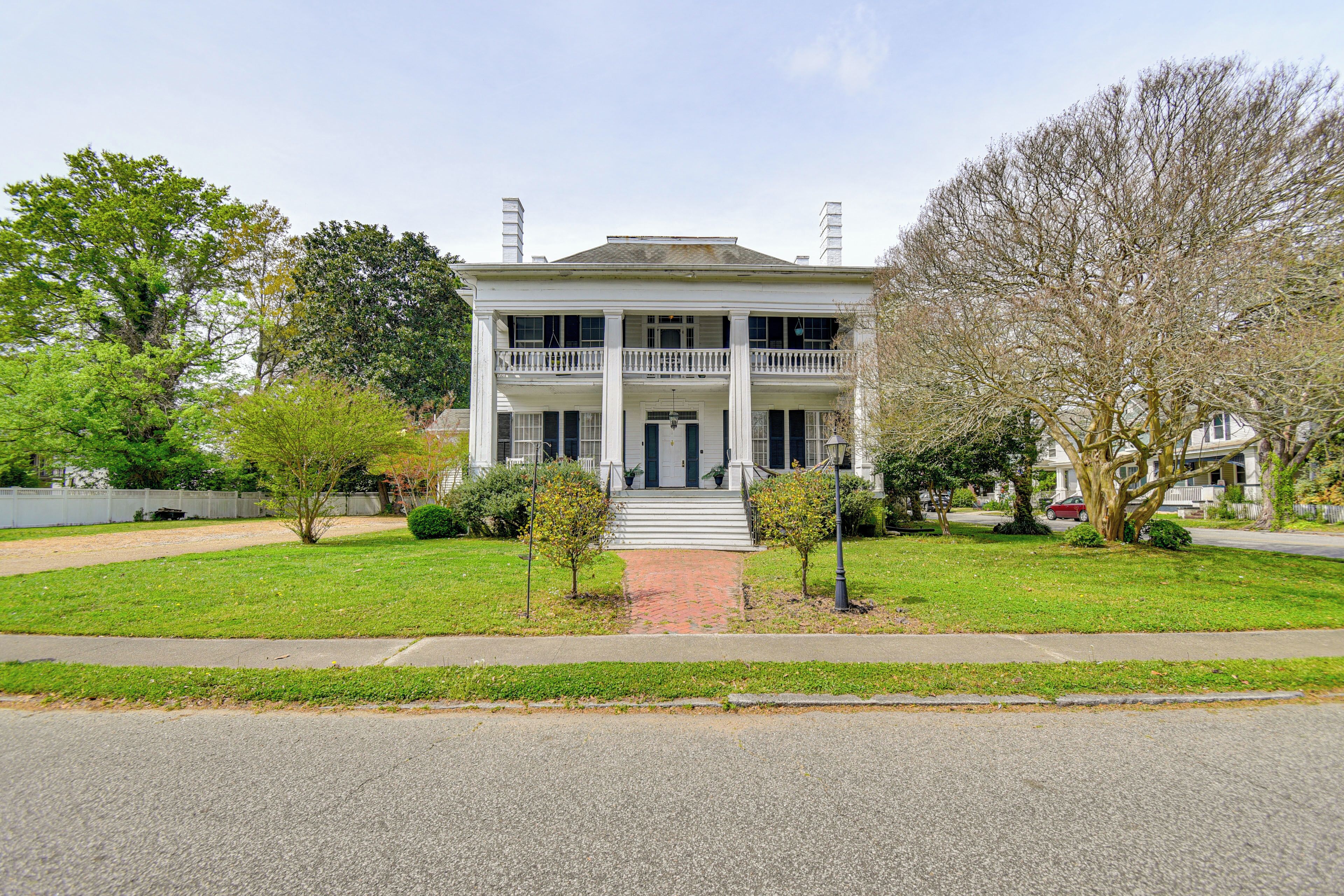 A two-story house with a front porch, a brick pathway leading to the entrance, and a well-maintained lawn.