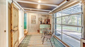 Une pièce dotée d’une grande fenêtre, d’une porte en bois, d’un tapis à motifs et d’une petite table avec des chaises.