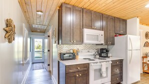 Une cuisine moderne avec des meubles en bois foncé, des appareils électroménagers blancs et un dosseret de carrelage disposé en motif chevron.
