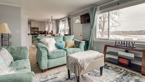 A living room with teal sofas, a coffee table, and a TV stand with a 'FAMILY' sign.
