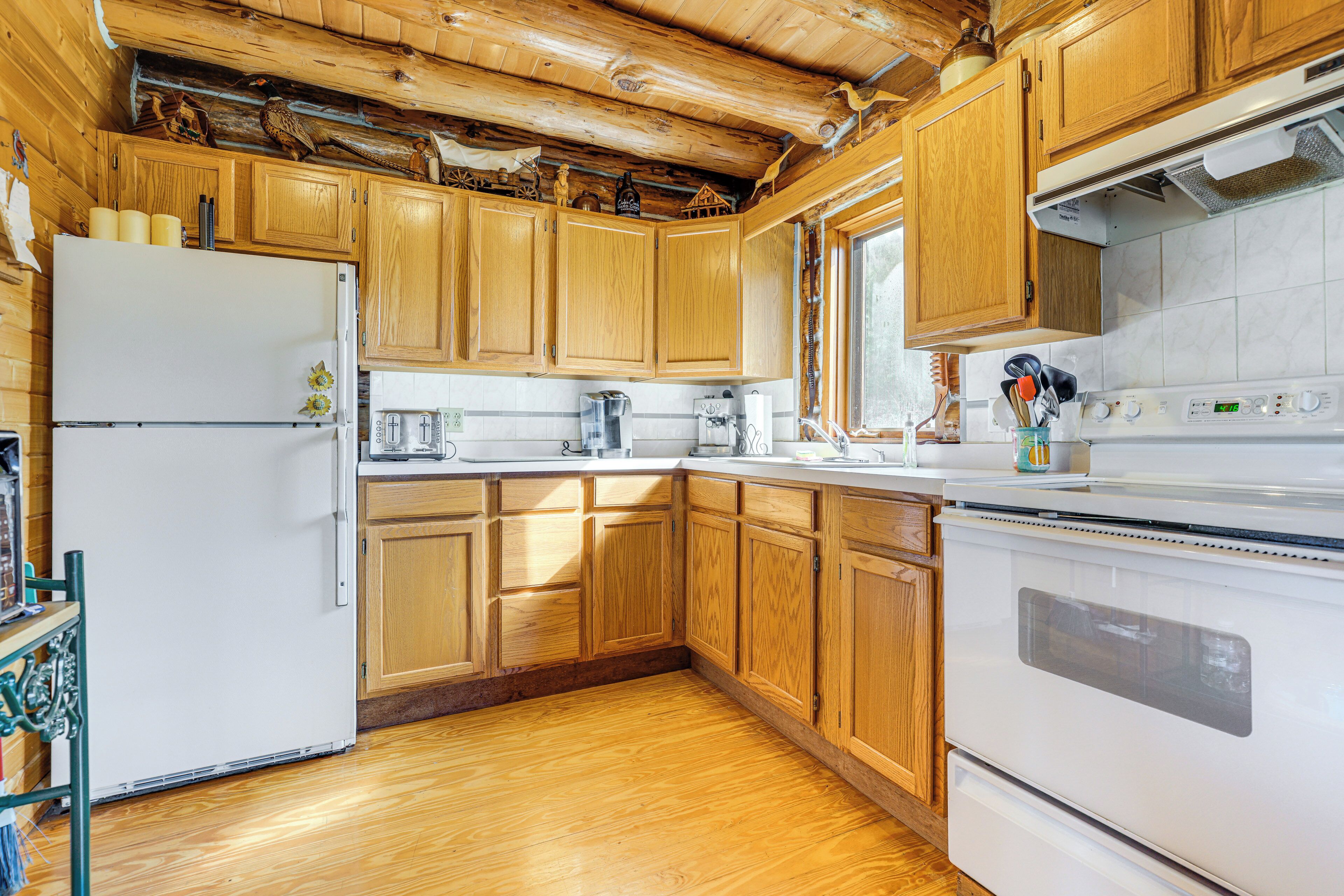 A kitchen with wooden cabinets, a white refrigerator, and a stove.