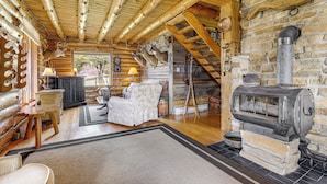 Ein Blockhaus-Interieur mit Kamin, Holzmöbeln und einer Steinwand.
