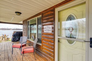 A wooden deck with outdoor seating and a view of a lake.