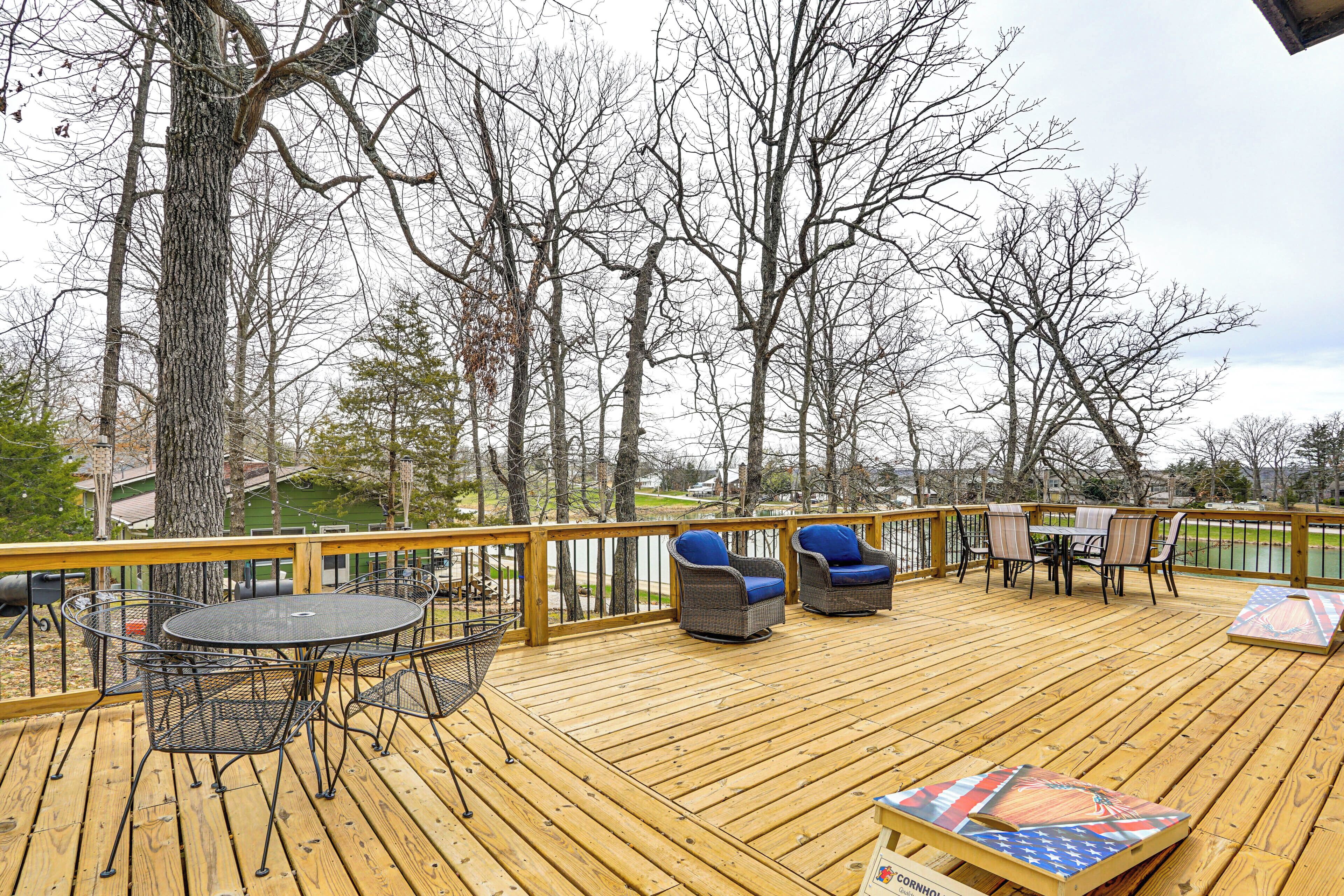 Een houten terras met buitenmeubilair, zoals een tafel en stoelen, met uitzicht op water en bomen.