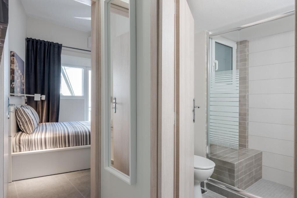 Une salle de bain moderne dotée d’une douche à parois de verre, de toilettes et d’un espace douche avec un sol carrelé.