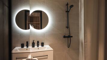 Un baño con espejo, lavabo y ducha.