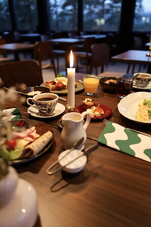 A dining table set with plates of food, a cup of coffee, a candle, and a pitcher of water. - Kelo Resort  (Enontekio)