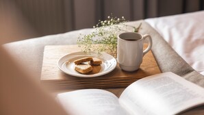 Un livre, une assiette de biscuits et une tasse de café sur une table en bois.