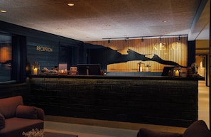 A reception area with a wooden reception desk, a computer, and a wall-mounted sculpture. - Kelo Resort (Enontekio)