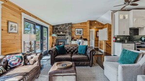 A cozy cabin interior with a fireplace, leather sofas, a dining area, and a kitchen. - Screened-Porch Home, Killington Views & Pet-Friendly (Hartford)