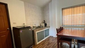 A compact kitchen with a refrigerator, microwave, and sink. There is a dining table with chairs and a window with blinds. - Spacious 2bdr BangTao House  (Choeng Thale)