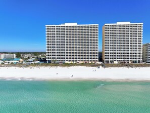 Un hôtel situé en bord de mer, avec plusieurs étages, une piscine et un espace de plage.