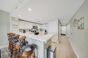 A modern kitchen with white cabinets, a central island, and bar stools.