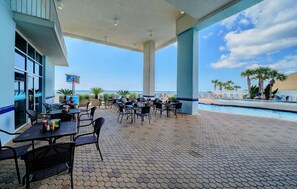 Un espace extérieur aménagé en terrasse, avec des carreaux hexagonaux, des tables, des chaises et une piscine.
