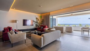 Una sala de estar moderna con un televisor de pantalla plana grande, varios sofás, una mesa de centro y un balcón con vistas.