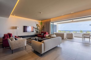 Un salon moderne doté d’un grand téléviseur à écran plat, de plusieurs canapés, d’une table basse et d’un balcon offrant une vue agréable.