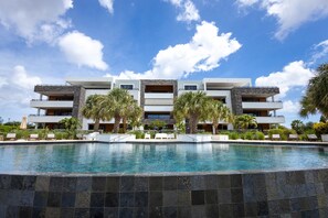Un hôtel moderne doté d’une piscine, de nombreux balcons et de palmiers.