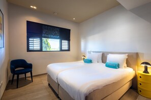 Une chambre moderne avec un grand lit, deux tables de chevet, une chaise et une fenêtre avec des stores.