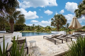 Un espace aménagé au bord de la piscine, avec des chaises longues, une petite table et un parasol.
