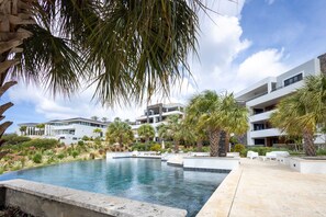 Un complexe hôtelier moderne doté d’une piscine, de palmiers et d’immeubles à plusieurs étages.