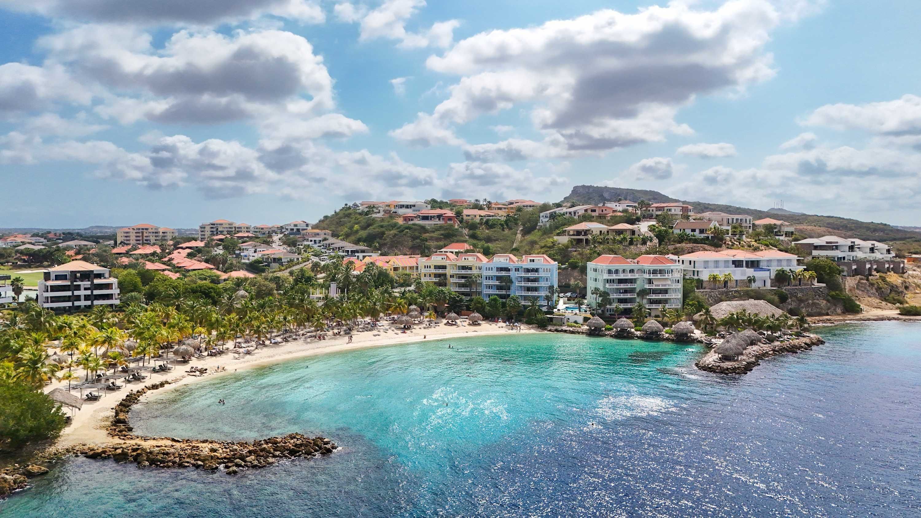 A coastal resort with beachfront villas, clear turquoise waters, and a sandy beach.