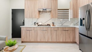 A modern kitchen with wooden cabinets, a stainless steel refrigerator, and a built-in stove.