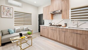 A modern kitchen with wooden cabinets, a built-in stove, and a large window with horizontal blinds.