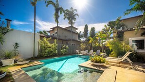 A backyard with a swimming pool, palm trees, and a house. - Bz91 Centro 600m Rua das Pedras piscina (Buzios)
