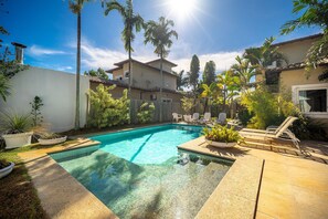 Una piscina al aire libre, sombrillas, sillones reclinables de piscina