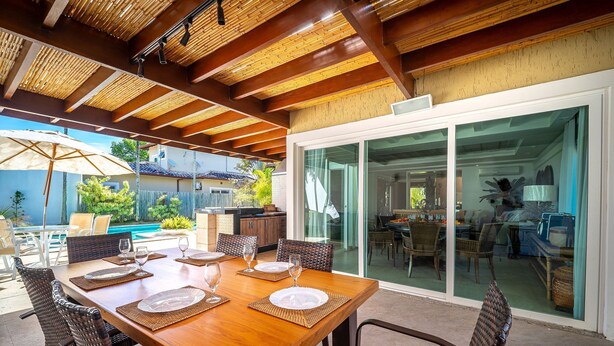 An outdoor dining area with a wooden table, wicker chairs, and a glass door leading to a patio. - Bz91 Centro 600m Rua das Pedras piscina (Buzios)