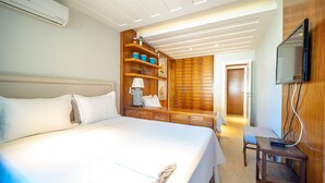 A hotel room with a large bed, wooden wardrobe, built-in shelves, a desk, and a TV mounted on the wall. - Bz91 Centro 600m Rua das Pedras piscina (Buzios)