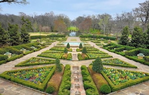 Ein formeller Garten mit geometrischen Hecken, einer zentralen Wasserspiele und einer symmetrischen Gestaltung.