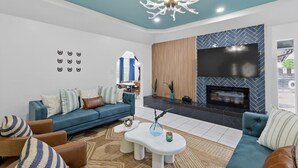 A modern living room with a blue sofa, white coffee table, and a fireplace.