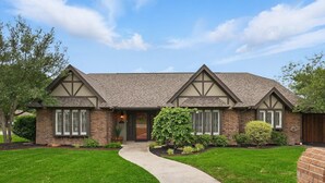 A two-story house with a brick exterior, a gabled roof, and a front entrance with a door and windows.