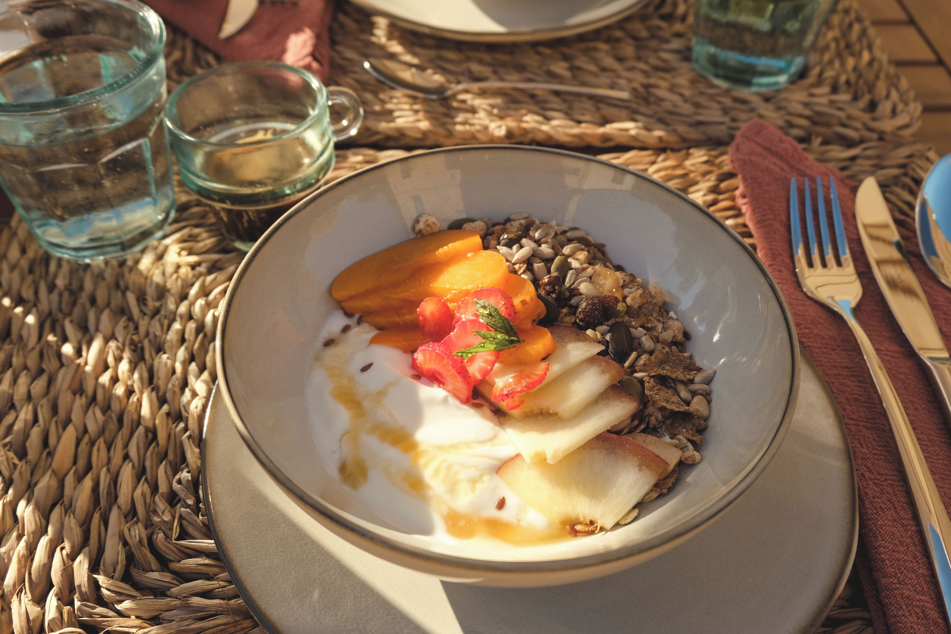 Eine Schüssel mit Früchten und Nüssen auf einer gewebten Tischmatte.
